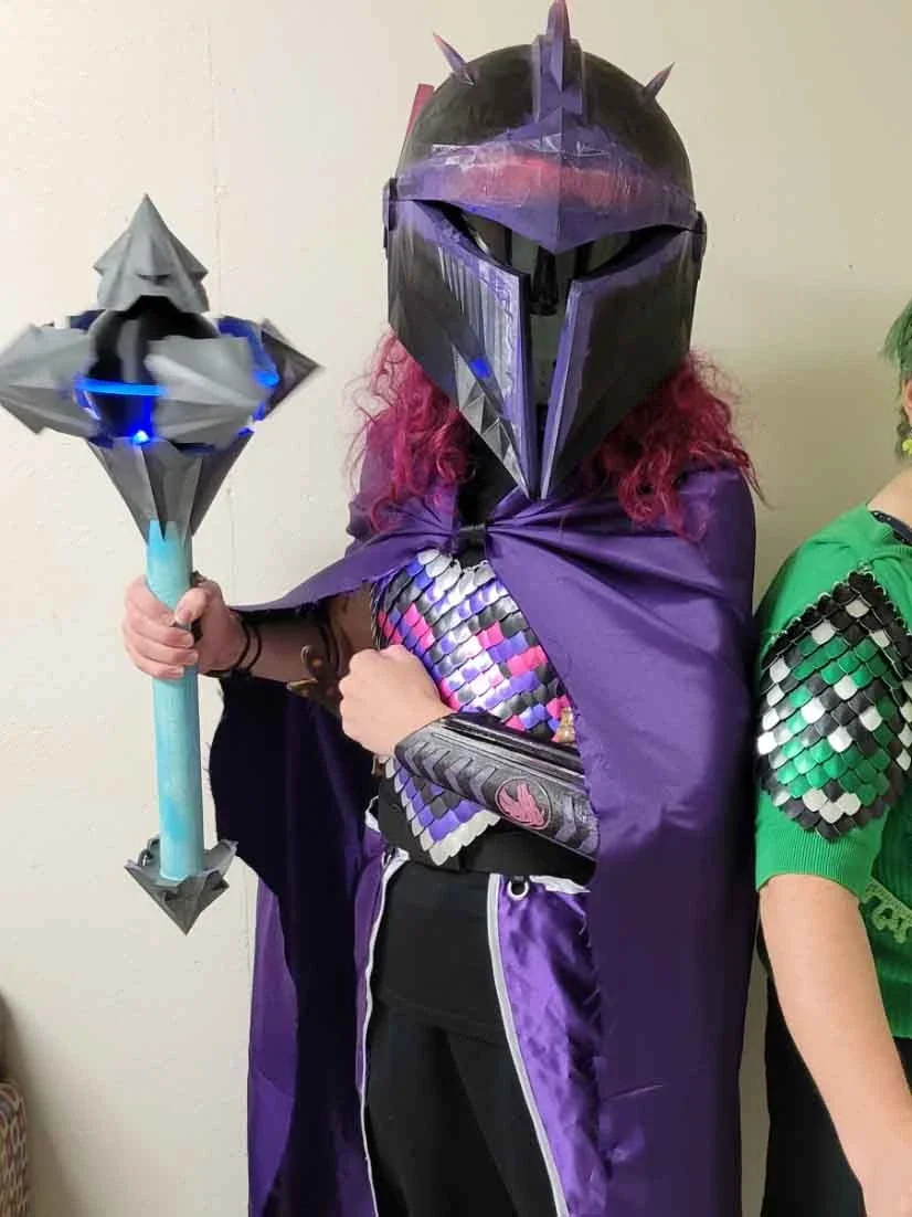 The costume comprised of a scalemail breastplate, a Mandalorian x Valkyrie inspired helmet, the Graviton Maul from Arcana Novum, a cape and two pieces of fabric that made a side skirt, and bracers. Everything was 3d modelled, printed, sewn, and crafted by me.